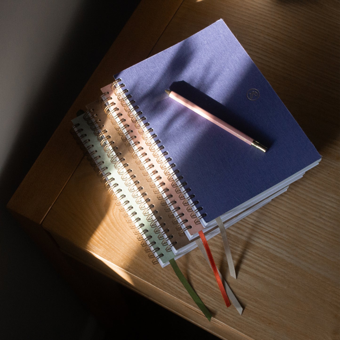 Stack of notebooks with pens on a wooden surface
